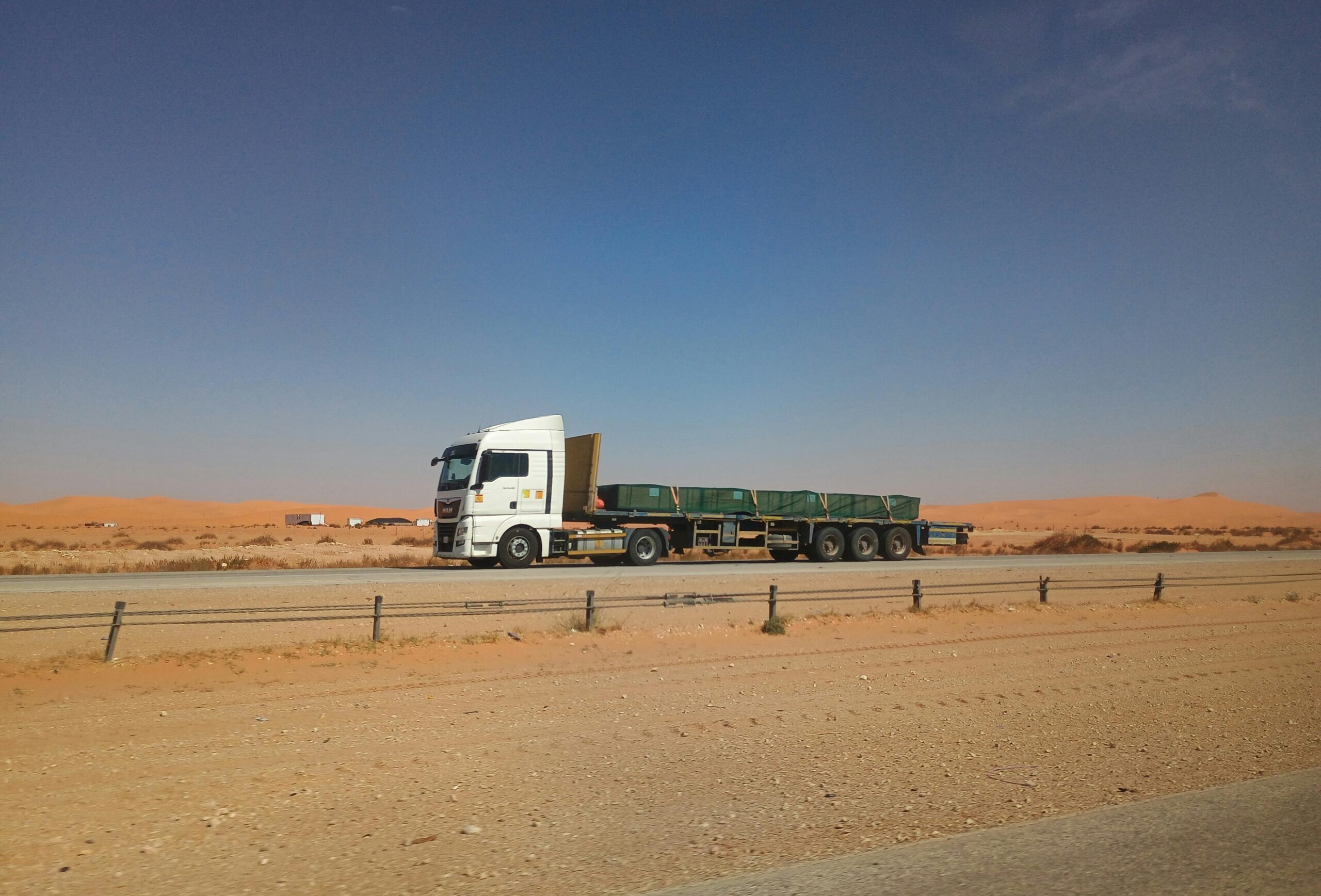 Flatbed truck on a desert highway in Eastern Province, Saudi Arabia under a clear sky.